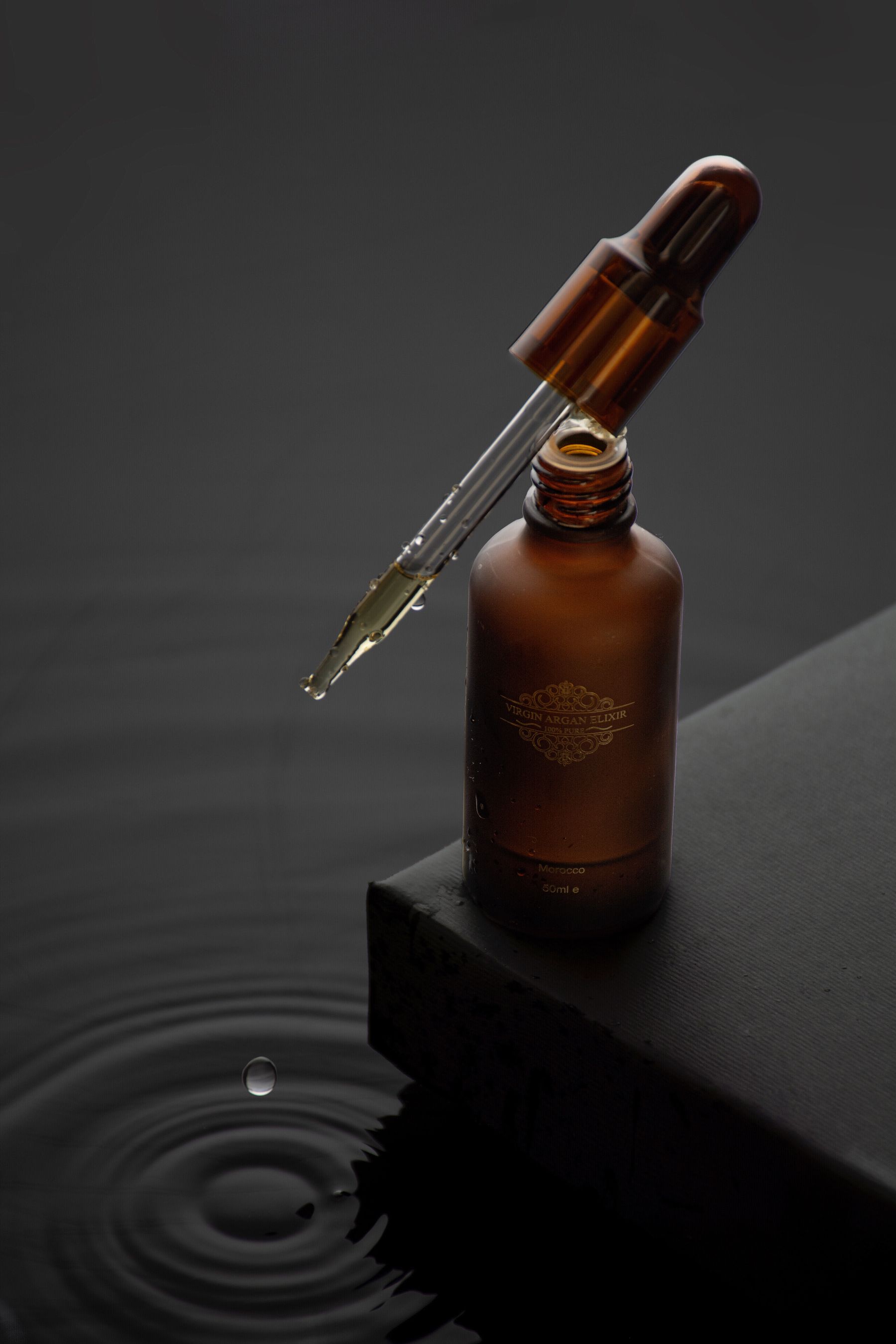 Amber apothecary serum in a reflective water setting